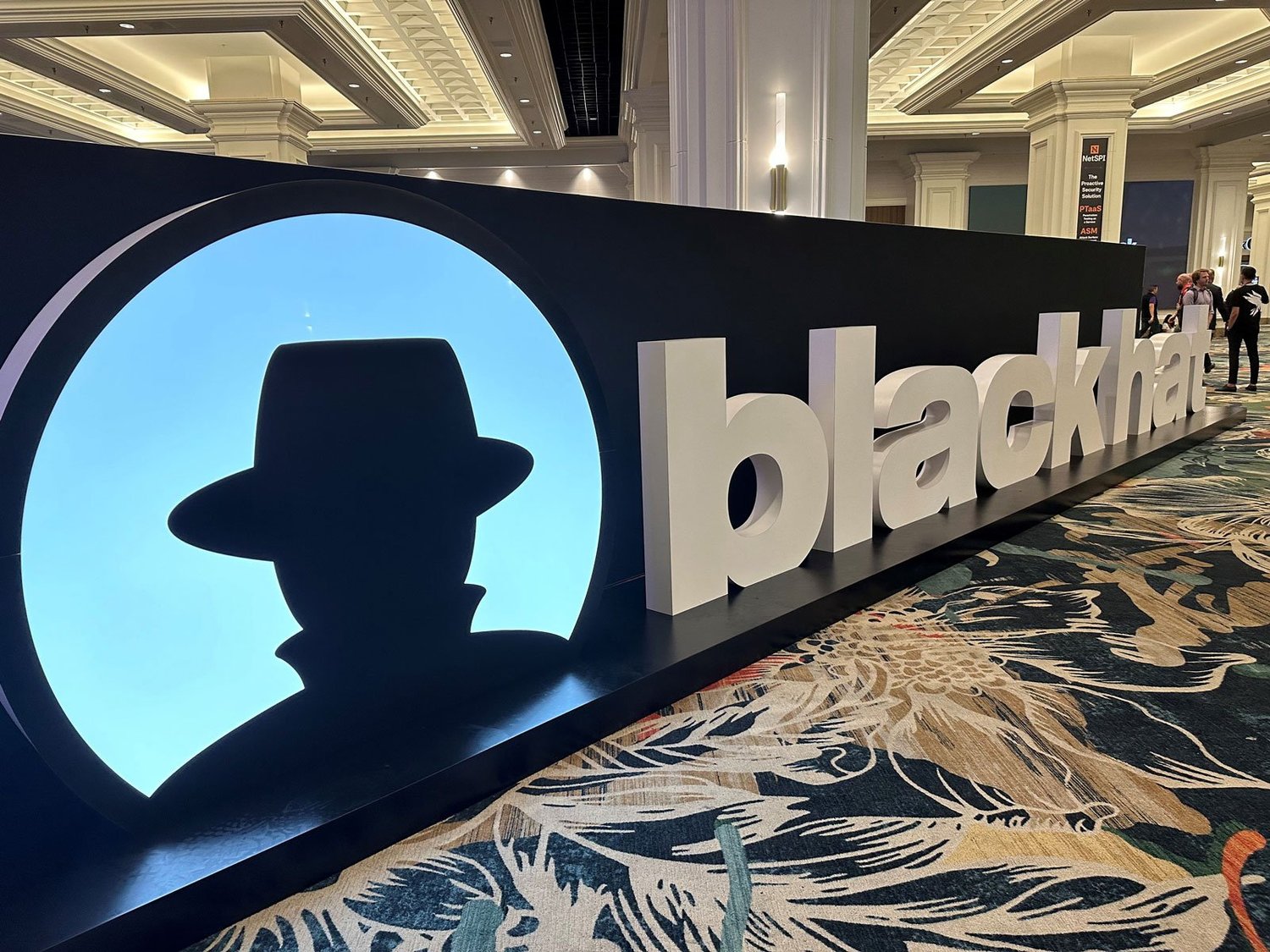 A large BlackHat logo display in the middle of a hotel convention.